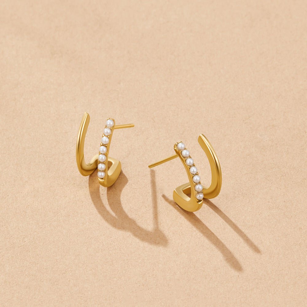 18K Gold & Pearl Claw Earrings, a pair of gold earrings lying flat on a beige surface, one with a row of small pearls