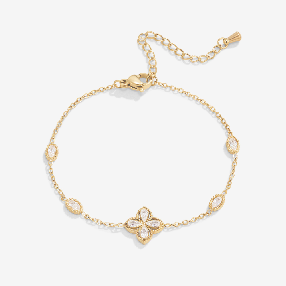 Four Leaf Clover Crystal Bracelet, flat lay of gold chain bracelet with clear stone flower motif