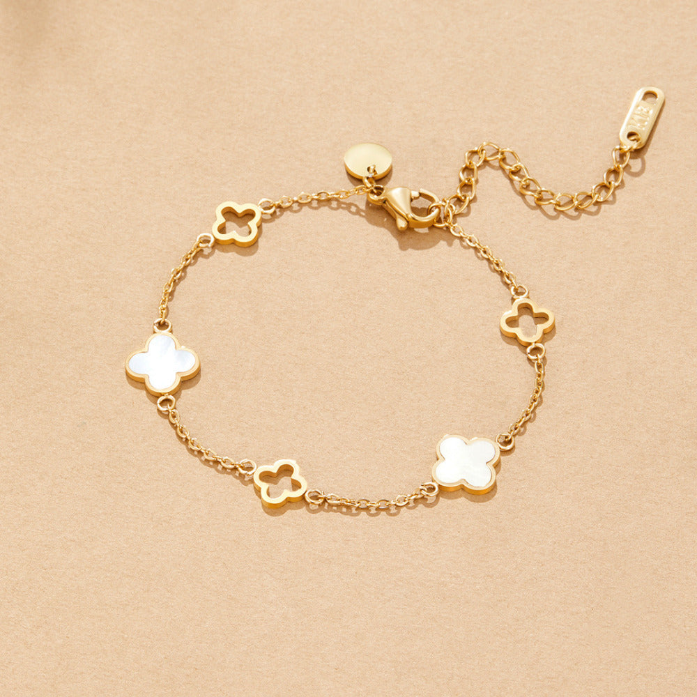 Lucia Clover Bracelet, laid flat on a beige surface, gold chain with clover charms