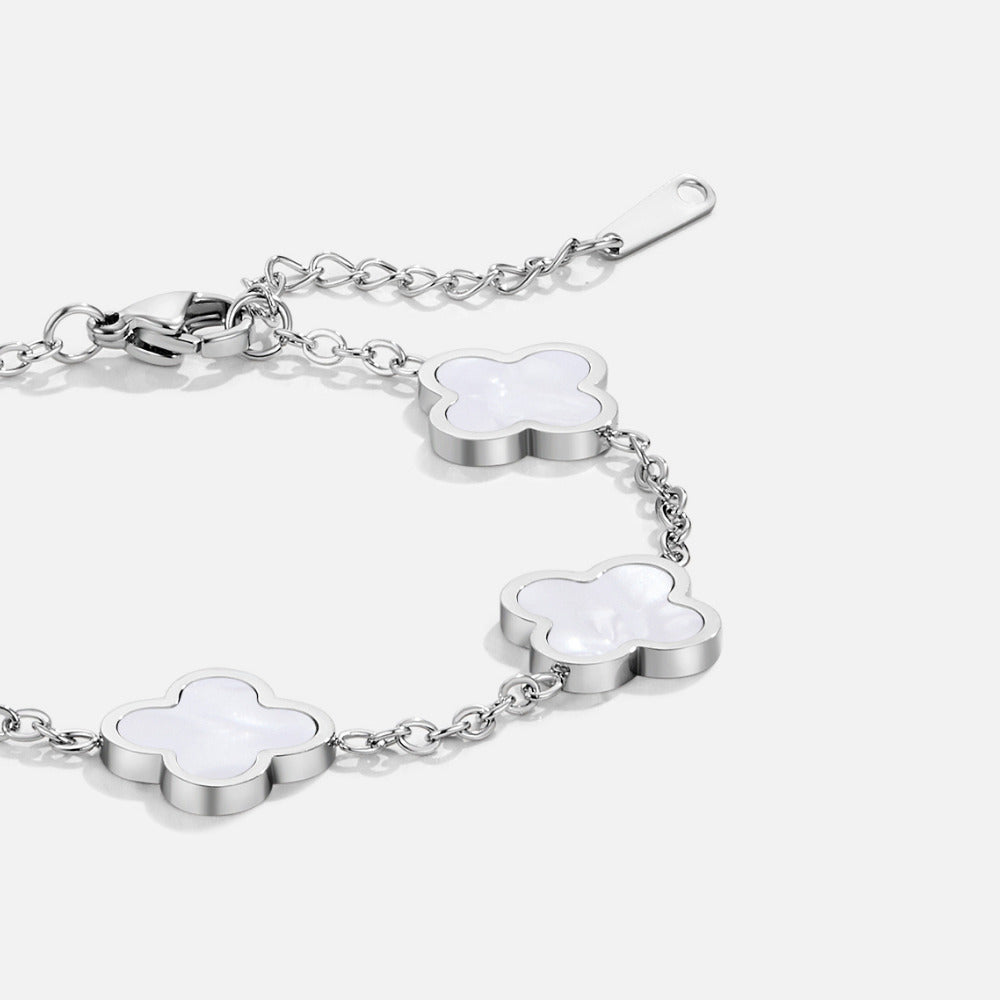 Silver Clover Bracelet, silver chain bracelet with white four-leaf clover motifs, laid flat on white