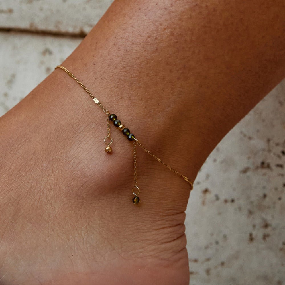 Arizona Green Bead Tassel Anklet, worn on an ankle with dark beads and gold drops