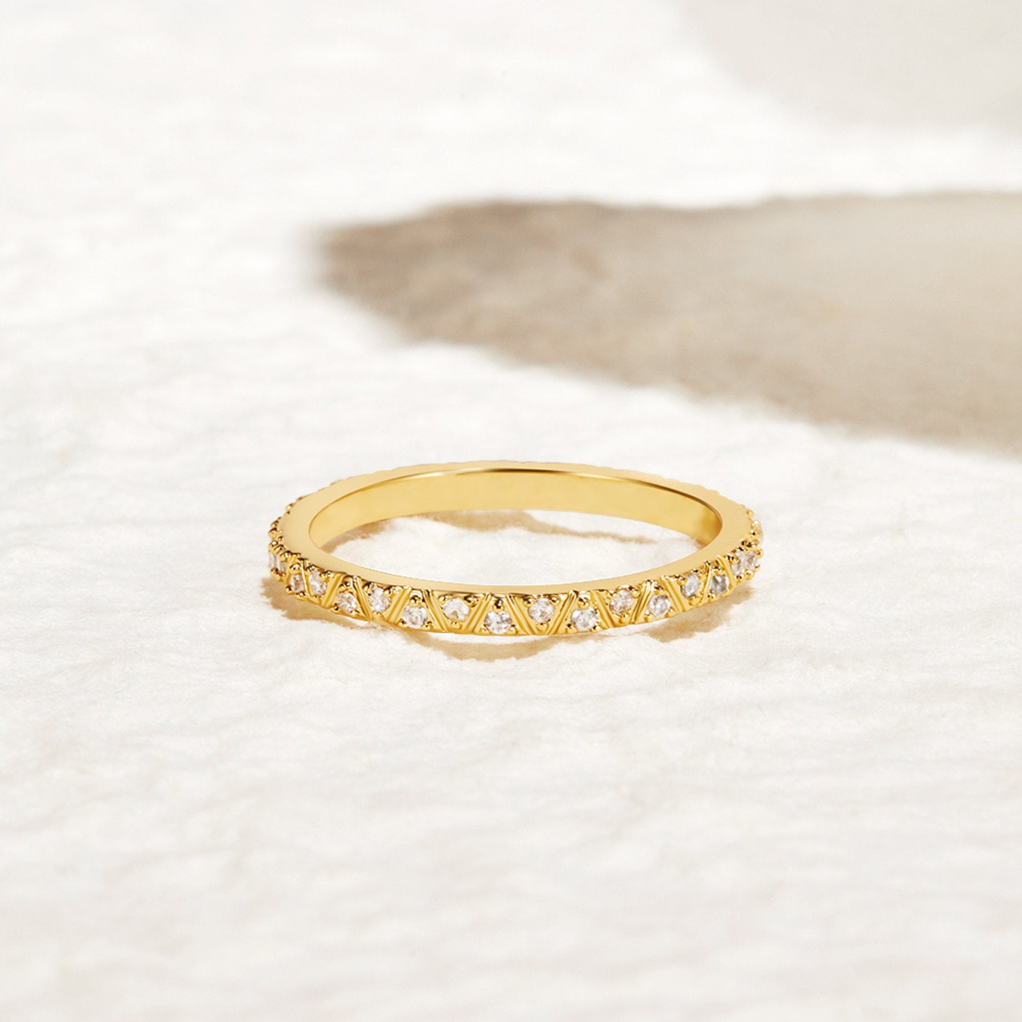 Arquette Gold & Crystal Band Ring, gold band with crystals set around it, resting on white