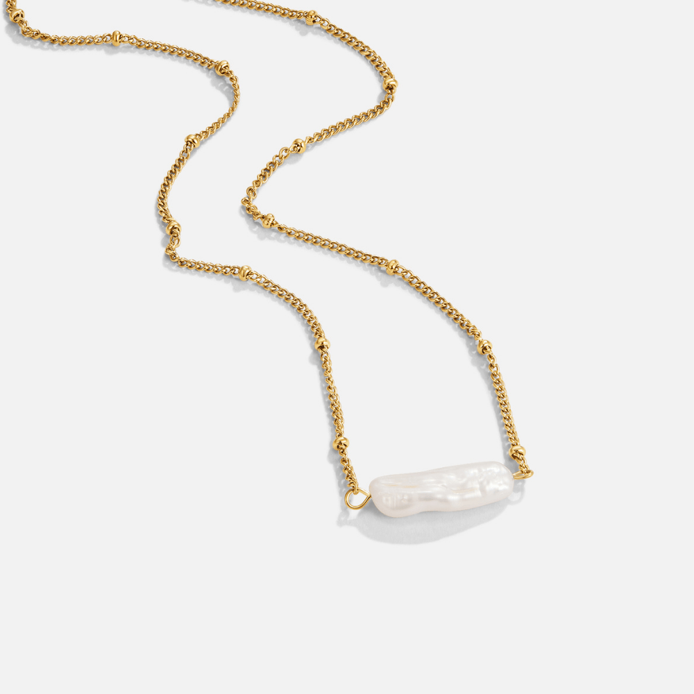 Atasha Baroque Pearl Necklace, gold chain necklace laid flat with a baroque pearl pendant on white