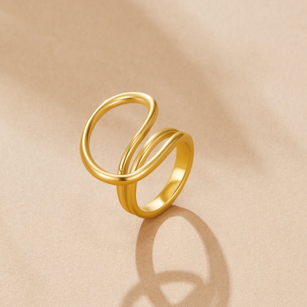 Ava Twisted Wave Ring, standing upright on a beige surface, polished gold wave design