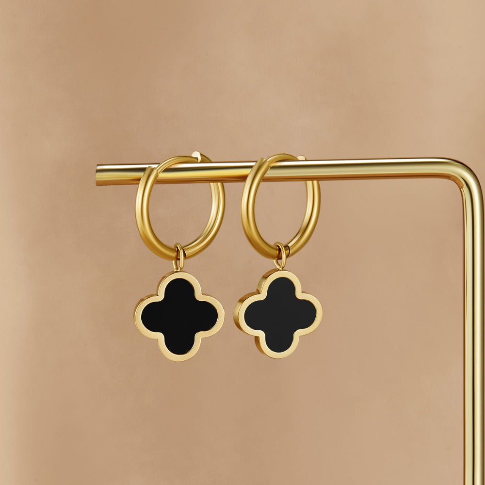 Black Clover Hoop Earrings, hanging on a gold display rod, black four-leaf clover charms