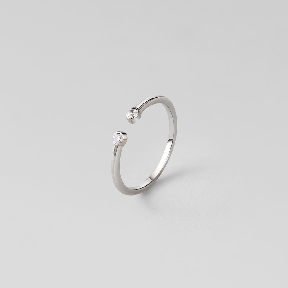Cali Silver Crystal Ring, open silver band with two small bezel-set clear stones, on grey