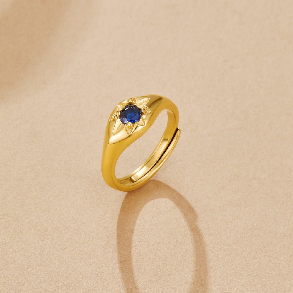 Celestial Blue Star Ring, gold ring with a round blue stone on a beige surface