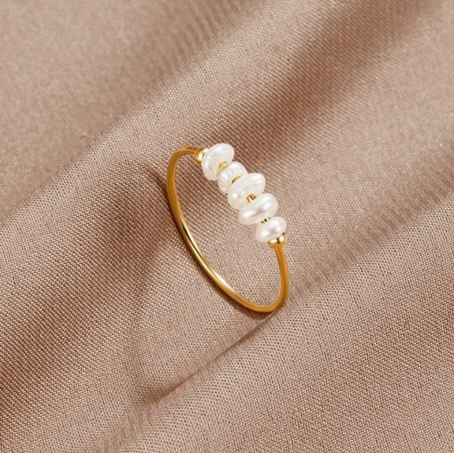 Classic Freshwater Pearl Ring, lying on beige satin with a row of white pearls