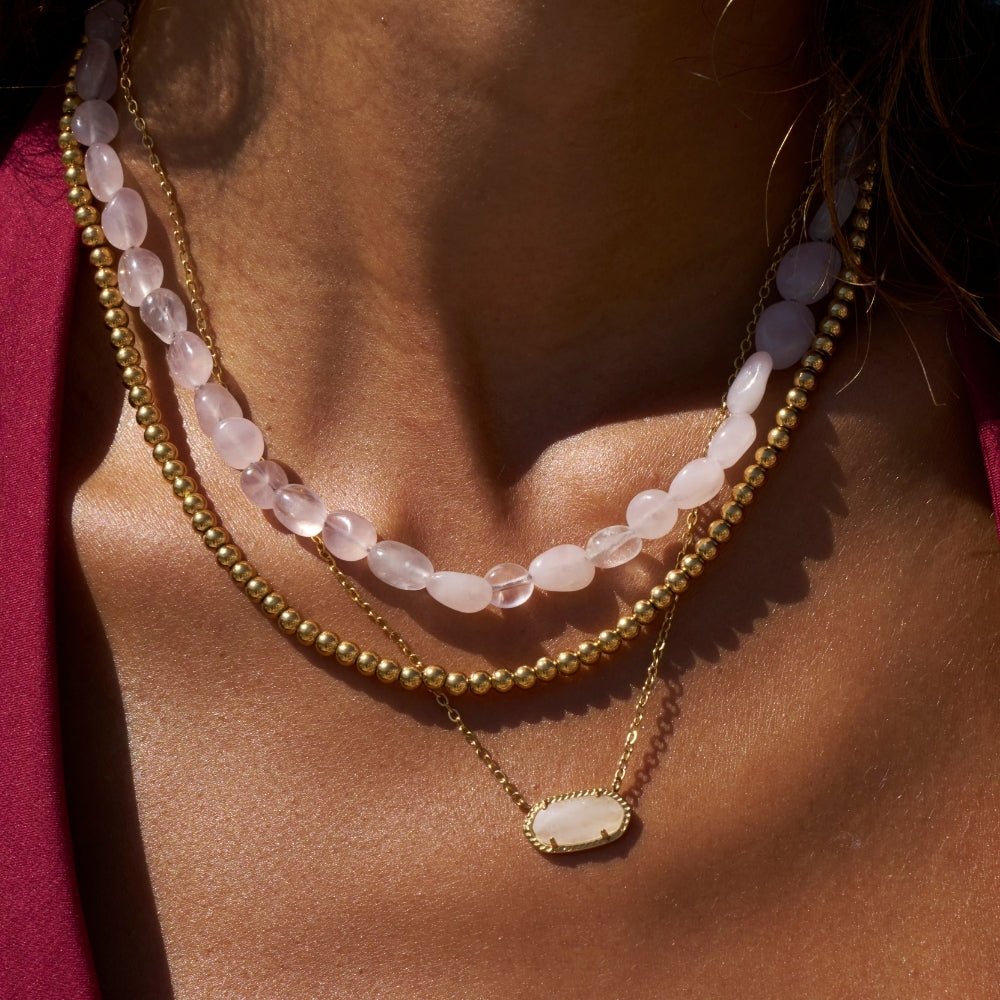 Coral Blush Stone Necklace, worn on a neck layered with gold beads and a pendant