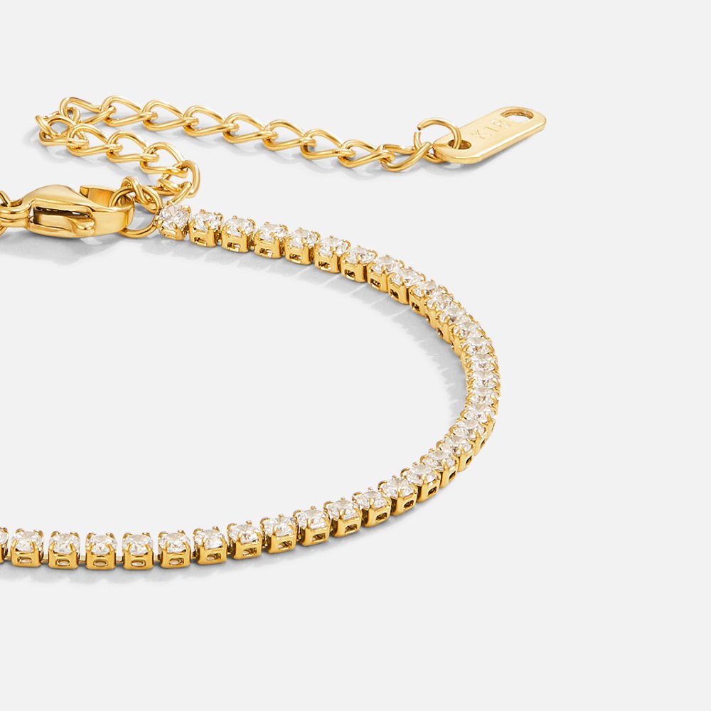 Cordelia Gold Tennis Bracelet, close-up of a gold tennis bracelet curving across white background