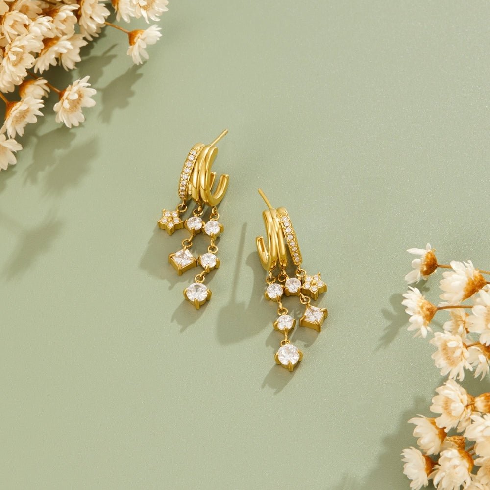 Crystal Bloom Triple Layered Earrings, flat-lay pair of gold earrings on sage green with dried