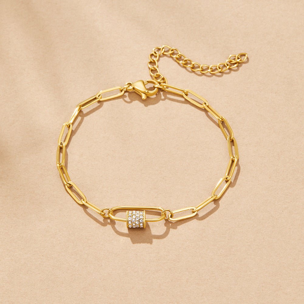Crystal Paperclip Charm Bracelet, flat lay on beige fabric, gold chain with a pave crystal charm
