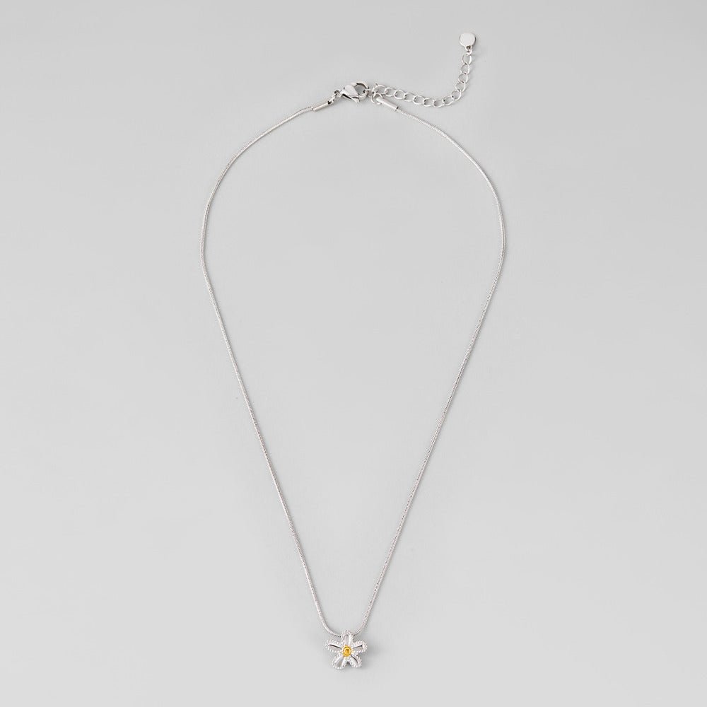 Daisy Pendant Necklace, laid flat on grey, silver chain with flower pendant and yellow centre