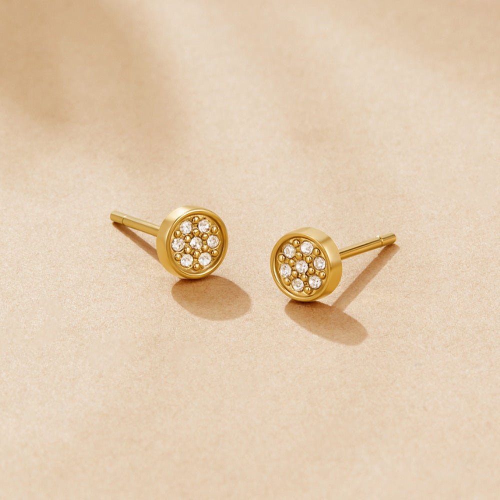 Elaine Crystal Disc Stud Earrings, a pair of stud earrings on a beige surface, with small