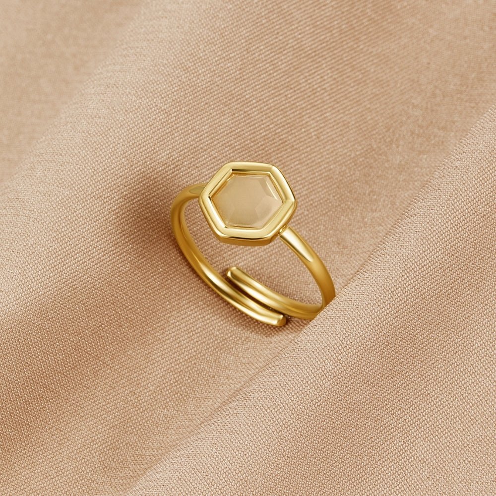 Ember Stone Gold Ring, gold ring with hexagonal pale stone, resting on beige fabric