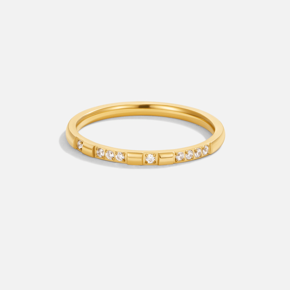 Emery Crystal & Gold Ring, gold band with small clear stones and bar accents, on a plain background