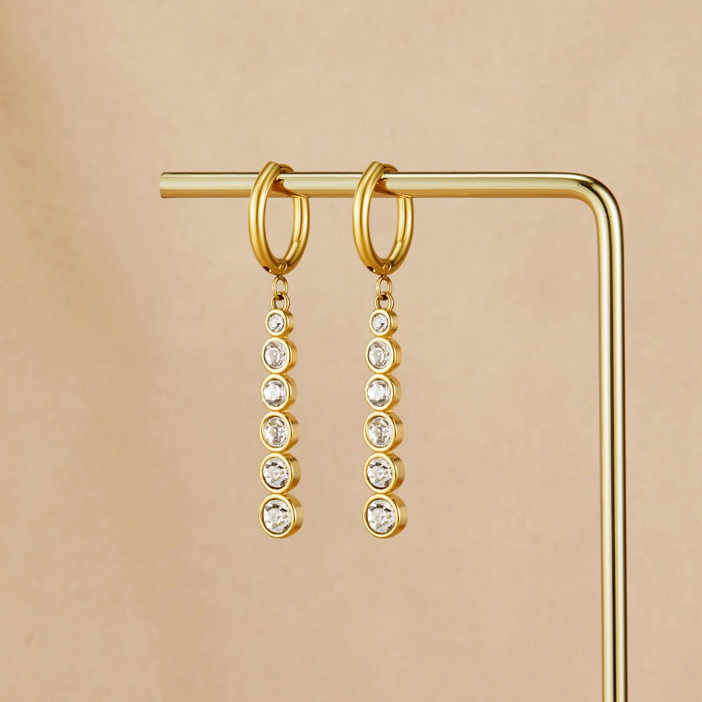 Emily Crystal Drop Earrings, hanging on a gold display rod, gold hoops with crystal drops