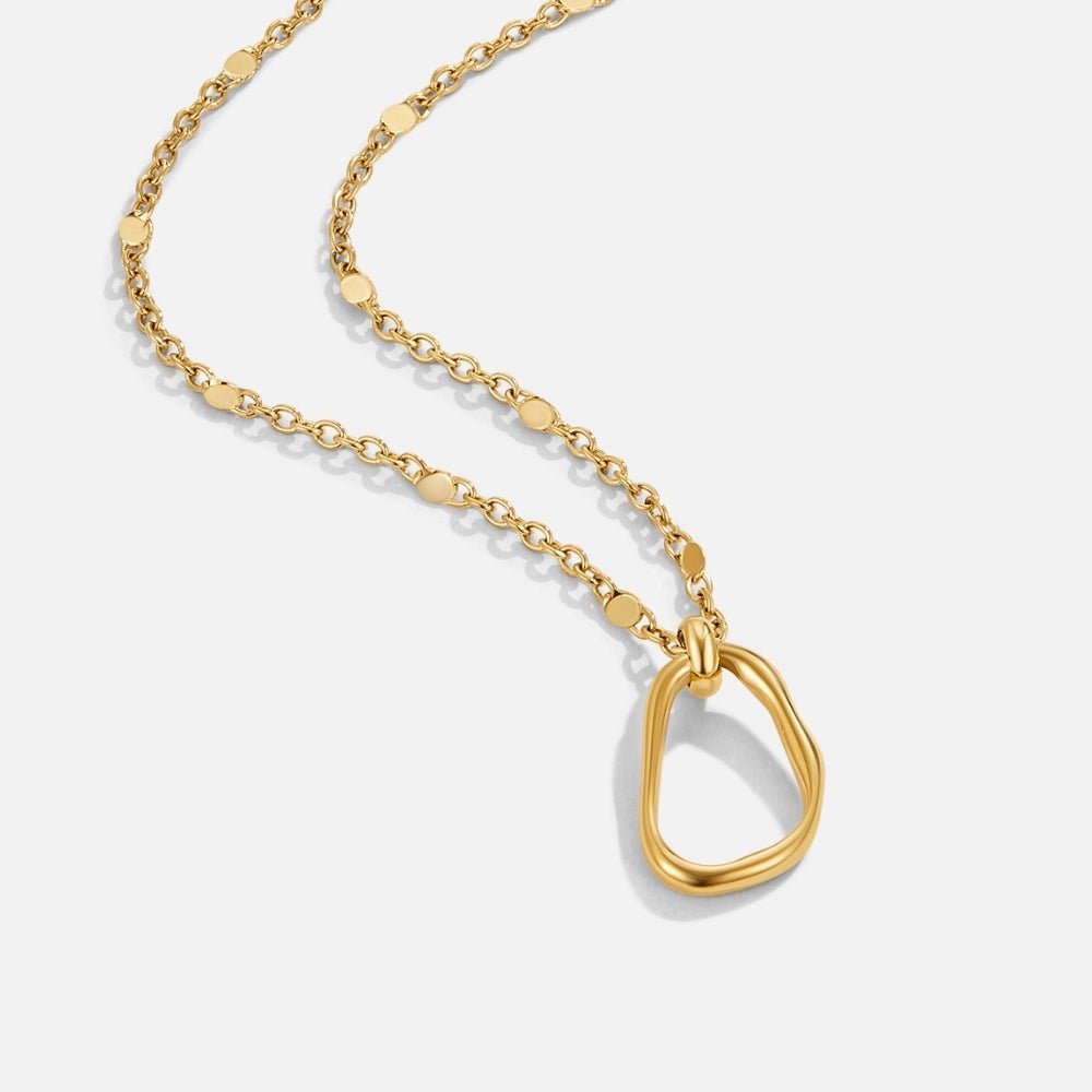 Erin Gold Pendant Necklace, gold chain with flat disc links and an open, wavy pendant on white