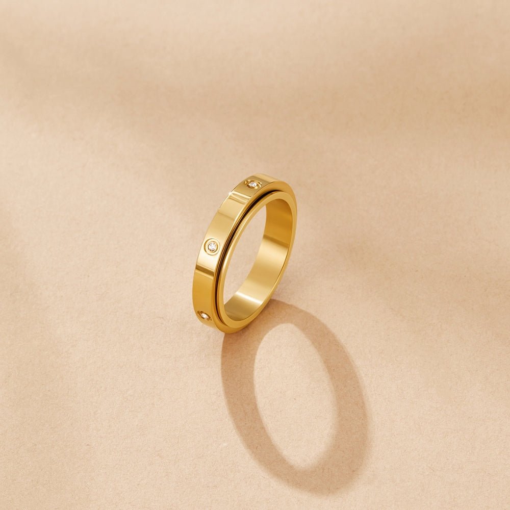 Eternity Love Band Ring, gold band ring standing upright on a beige surface, with small set stones