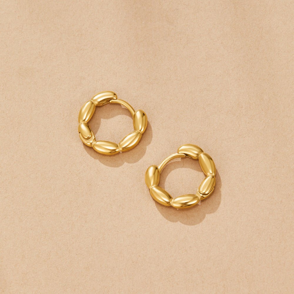 Evan Bead Hoop Earrings, pair of gold hoops with bead-shaped links, lying flat on tan paper