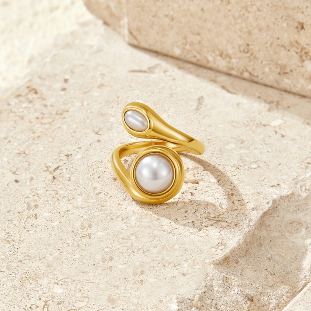 Gold Amara Pearl Wrap Ring, gold wrap ring with two pearls, resting on beige stone