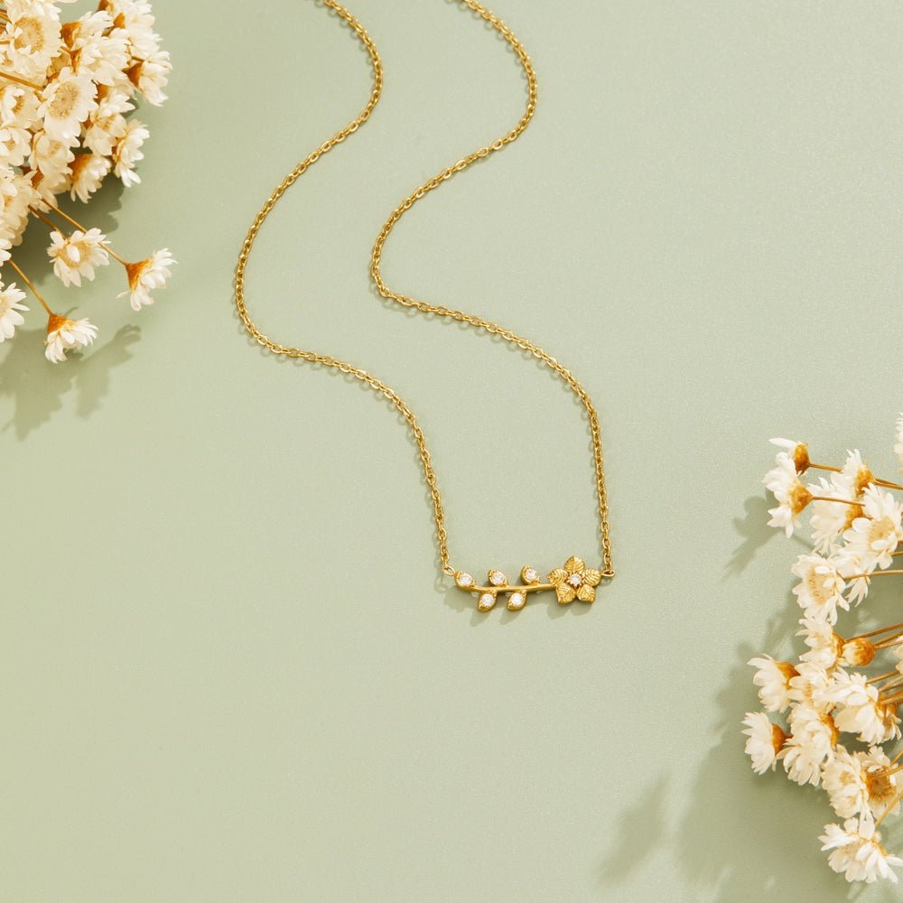 Golden Crystal Vine Necklace, laid flat on sage green with dried white flowers