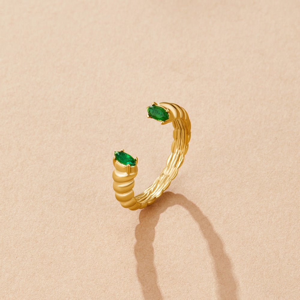 Green Emerald Cuff Ring, open gold ring with two green oval stones on a beige surface