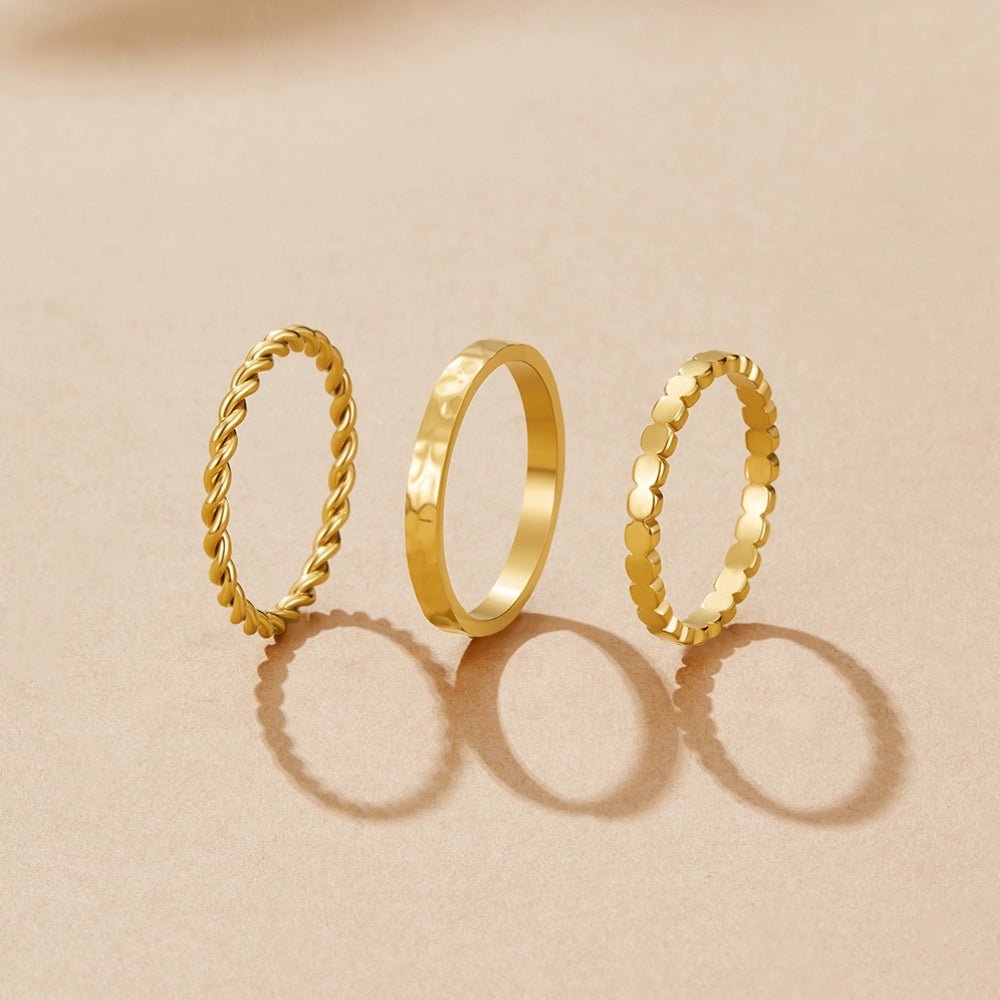 Hella Gold Stacked Ring Set, three gold stacking rings standing upright on a beige surface