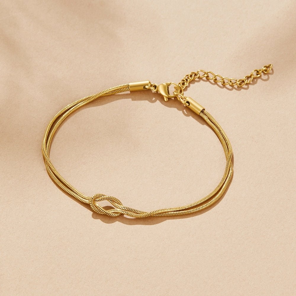 Knotted Gold Chain Bracelet, flat lay on beige fabric, gold double chain with a knot and extender
