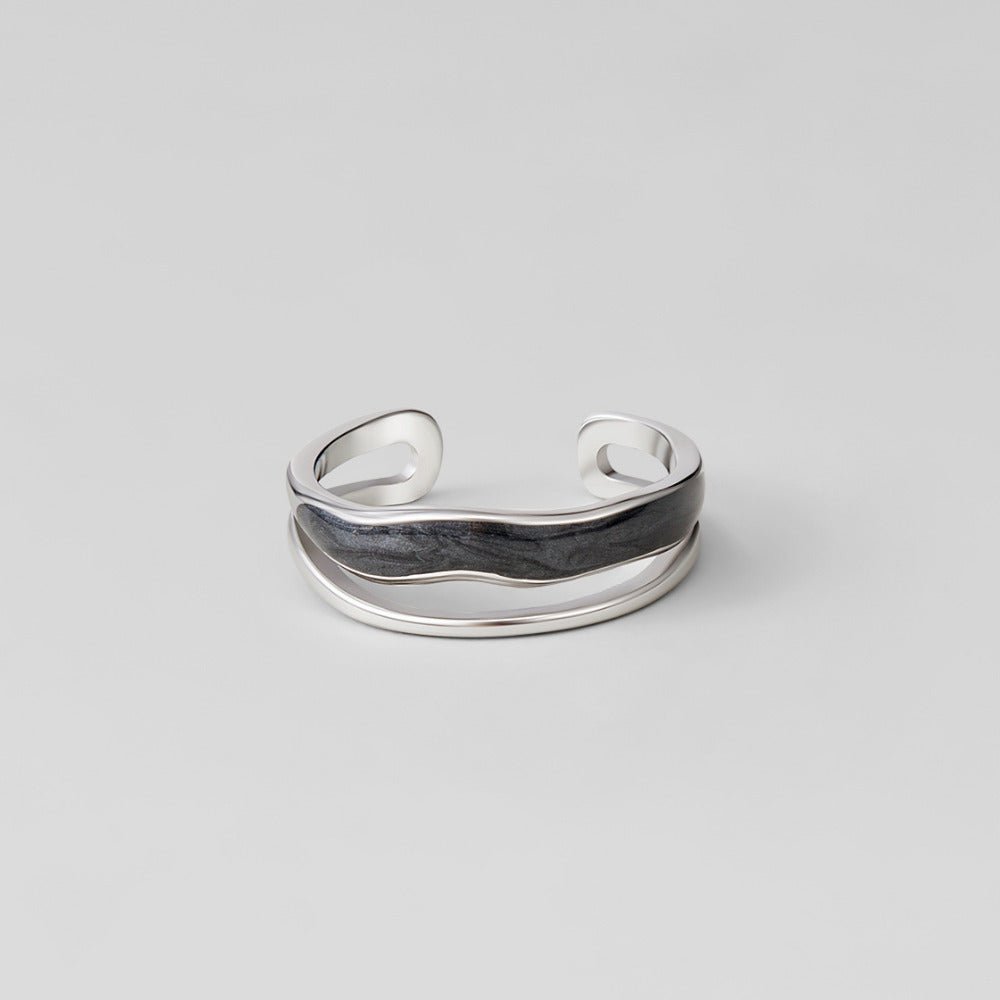 Layered Black Sahara Silver Ring, open silver band with wavy black inlay on a grey backdrop