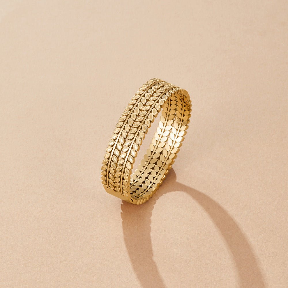 Layered Gold Leaf Bangle, standing upright on a beige surface, casting a shadow; gold leaf