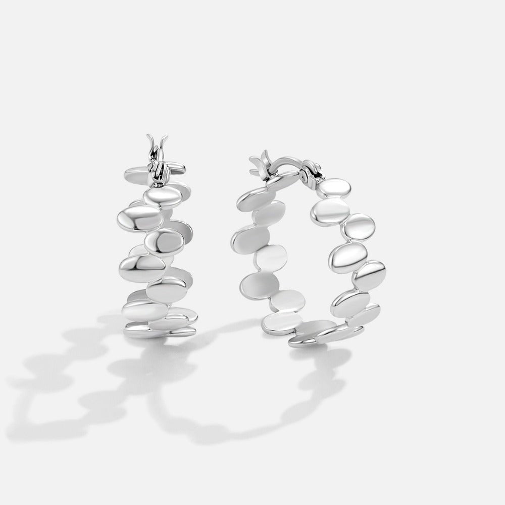 Link Monet Silver Hoop Earrings, a pair of silver hoops standing upright on a white surface