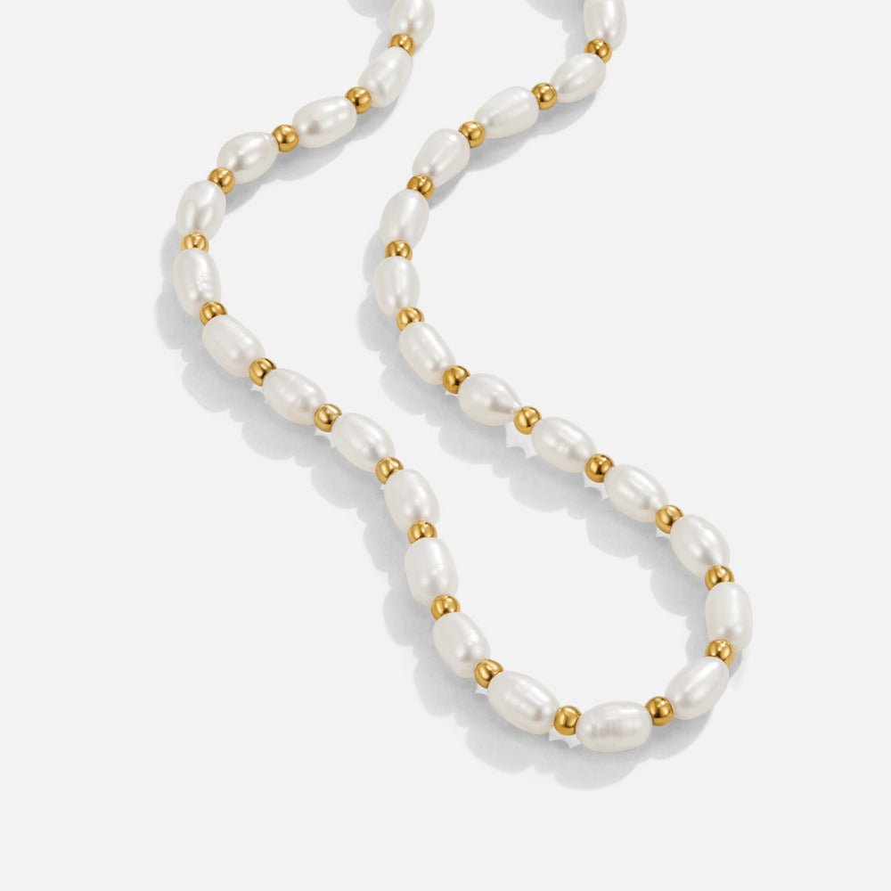 Malia Pearl Necklace, laid out in a flowing curve on white, oval pearls and gold beads