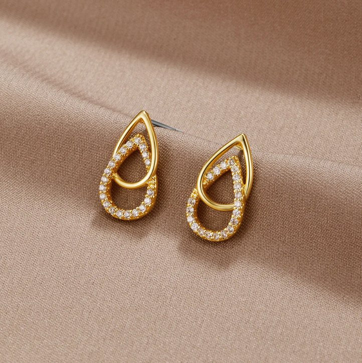 Mara Teardrop Link Earrings, a pair of earrings lying on a beige satin cloth, gold with