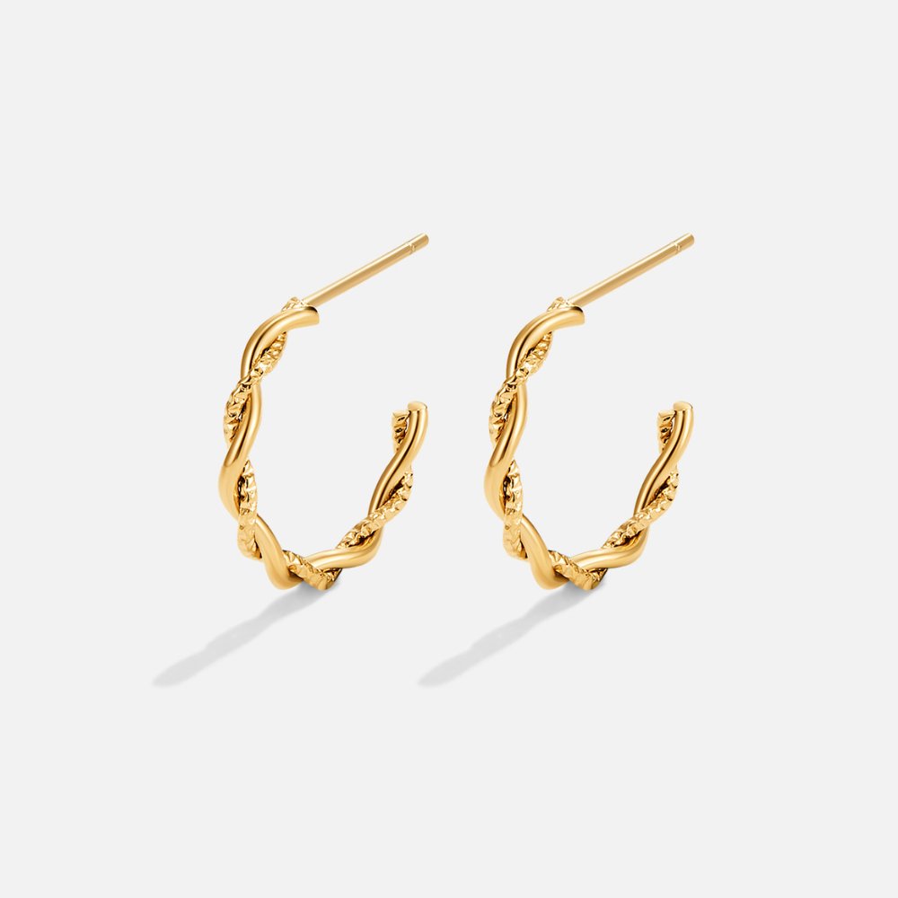 Maria Twisted Semi Hoop Earrings, pair of gold twisted semi-hoop earrings on a plain light