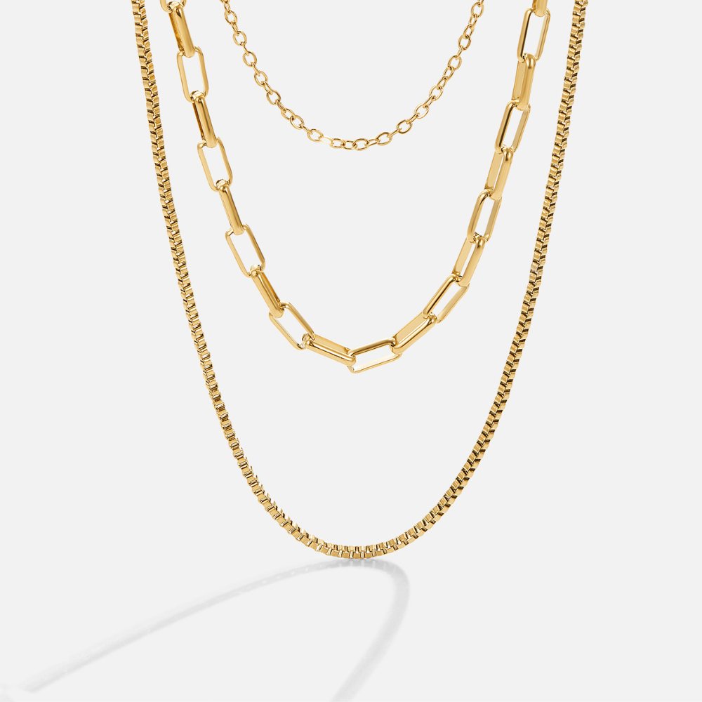 Miela Layered Chain Necklace, three gold chains layered together, on a plain light background