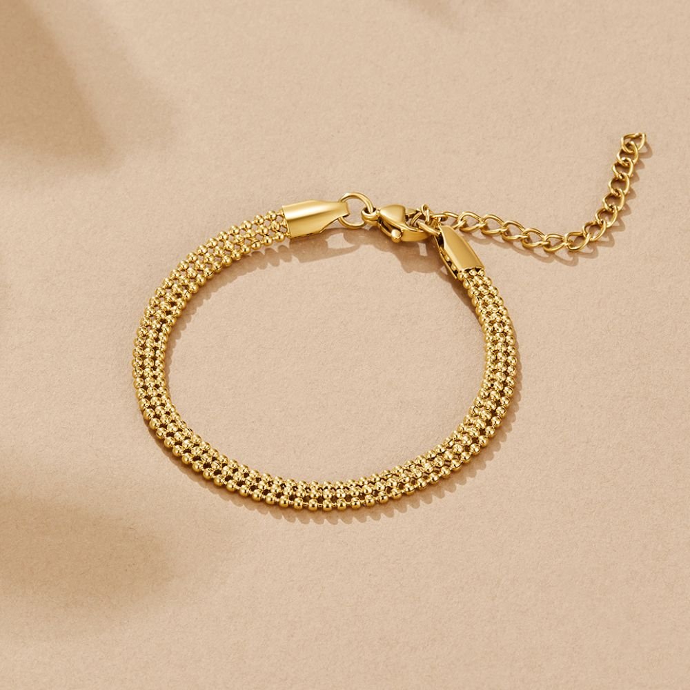 Milan Gold Beaded Chain Bracelet, laid flat on beige, clasp and extender chain visible