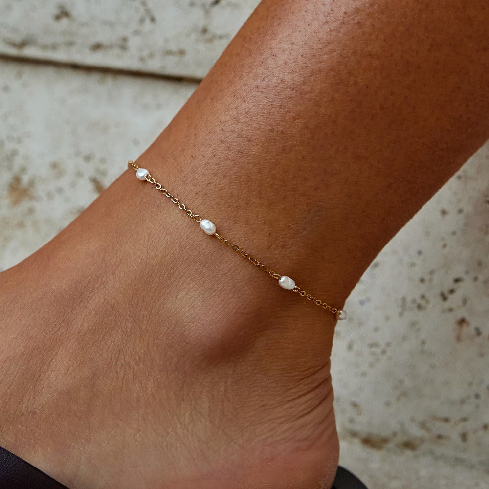 Nura Freshwater Pearl Anklet, worn on an ankle against a pale stone wall