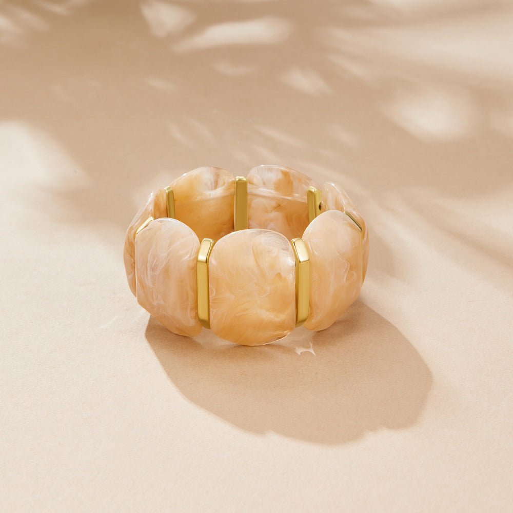 Odette Chunky Elastic Bangle, stretch bracelet lying flat on sand-coloured surface, cream