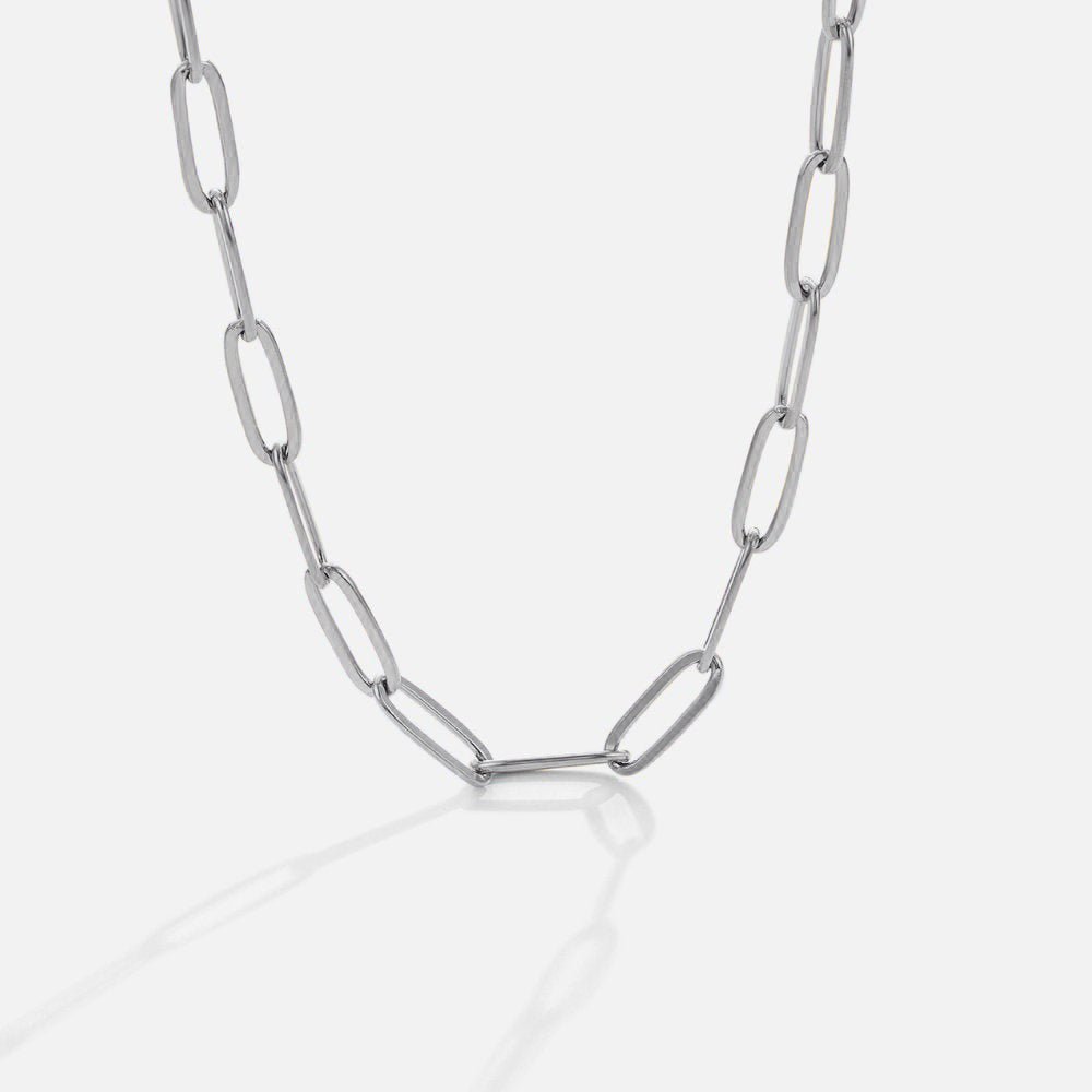 Paperclip Silver Necklace, lying in a curve on white, elongated oval links