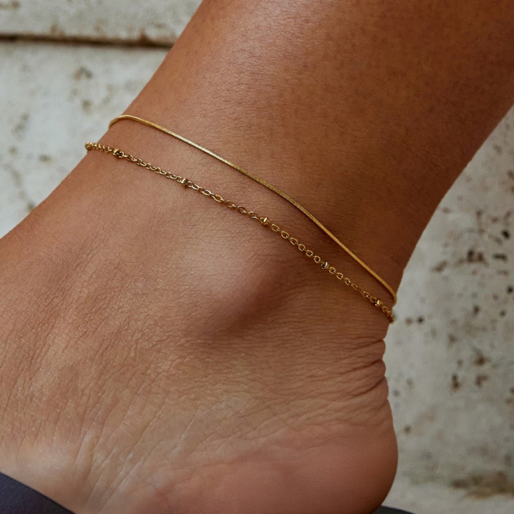 Pia Gold Layered Anklet, worn on an ankle, a thin snake chain and a dainty chain with small beads