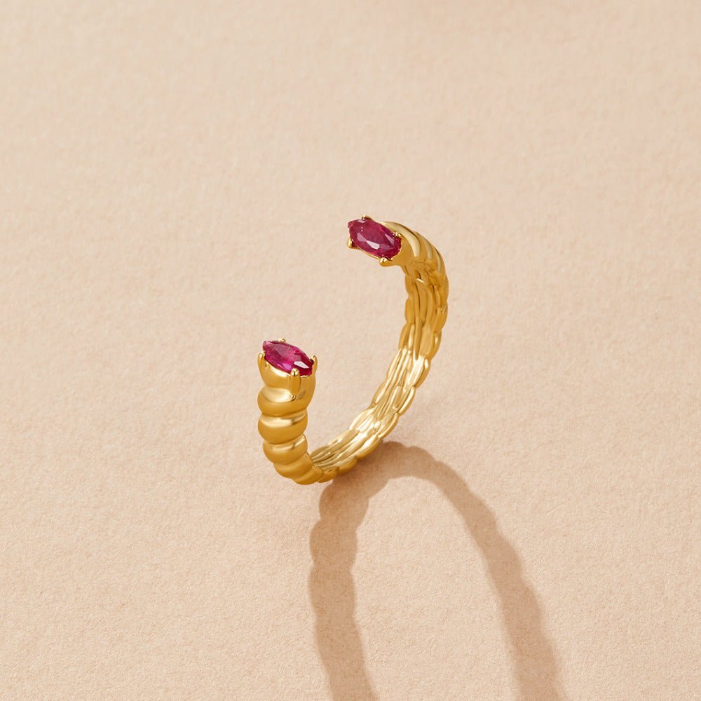 Pink Crystal Cuff Ring, open gold ring with twisted ridges and two pink oval stones, on beige