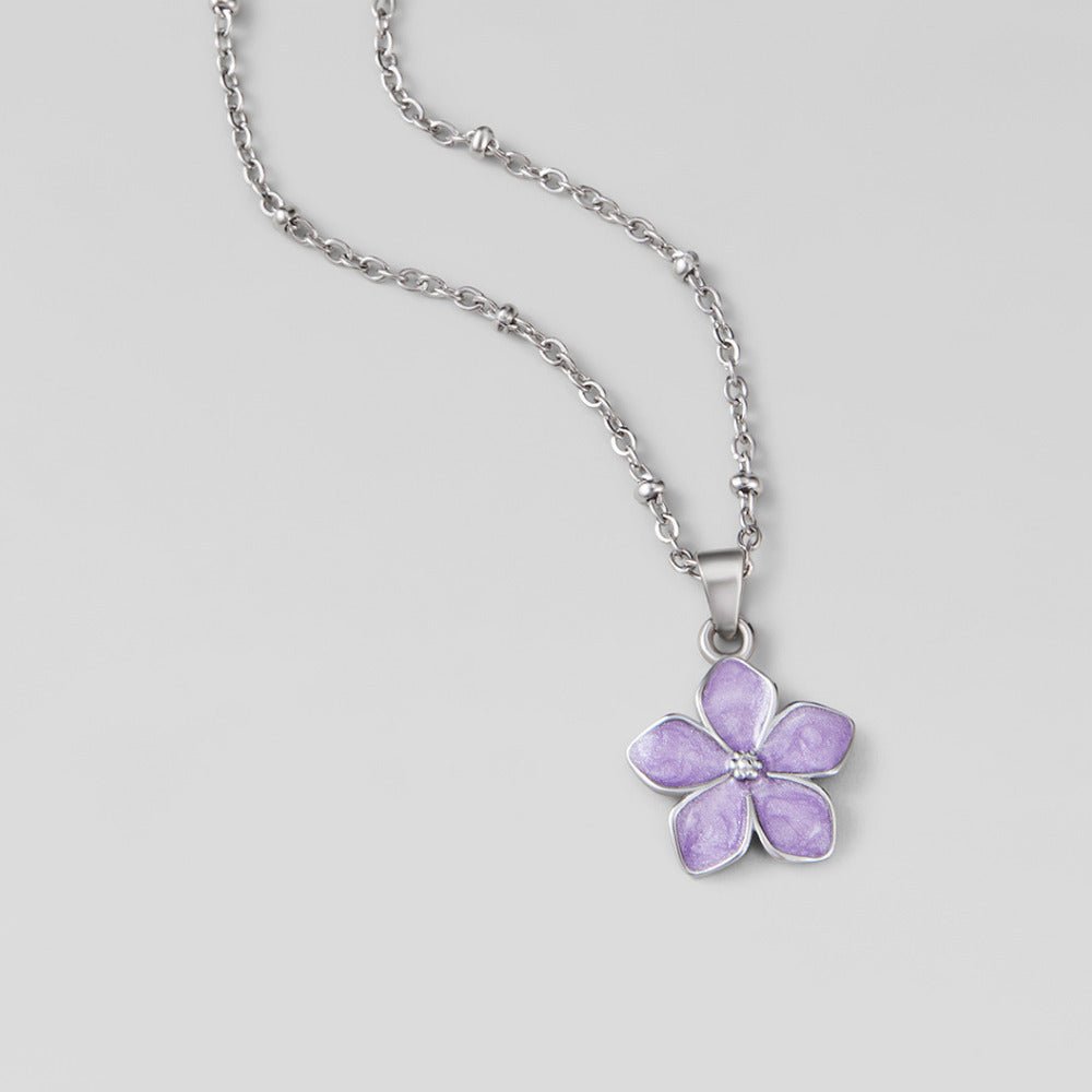 Purple Sakura Bloom Silver Necklace, flat on a grey surface, silver chain with lilac flower pendant