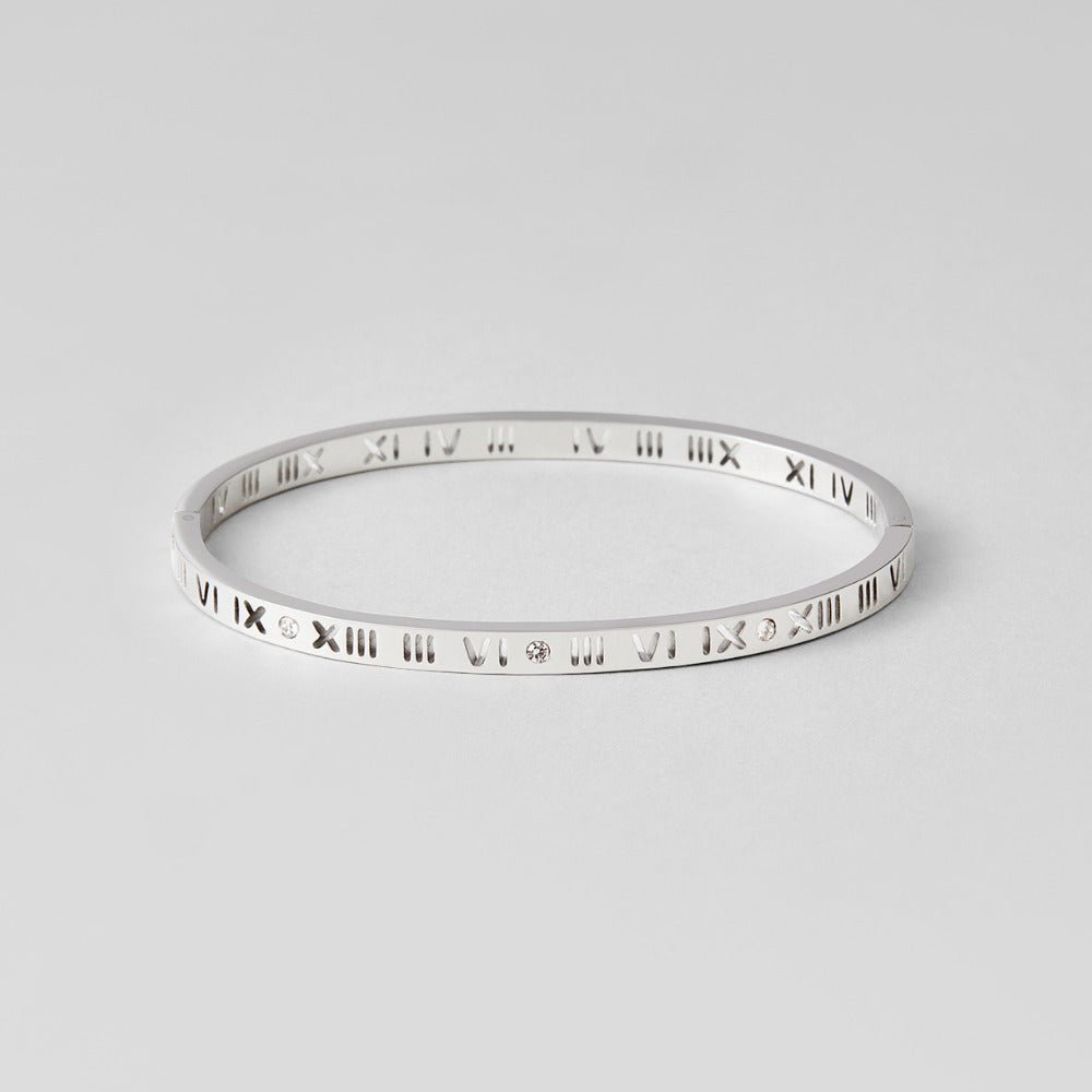 Roman Silver Bangle, silver bangle lying flat on grey, Roman numeral cutouts