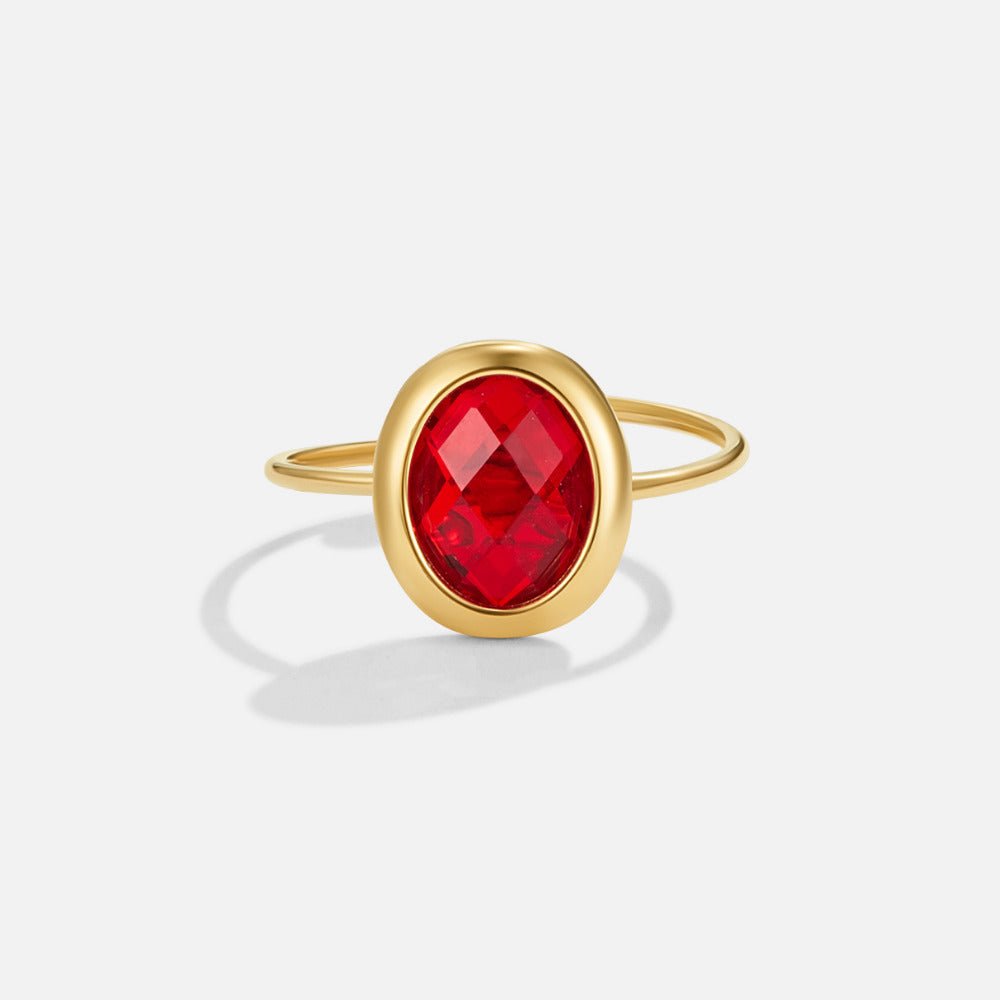 Ruby Crystal Gold Ring, standing upright on white, gold band with oval red faceted stone