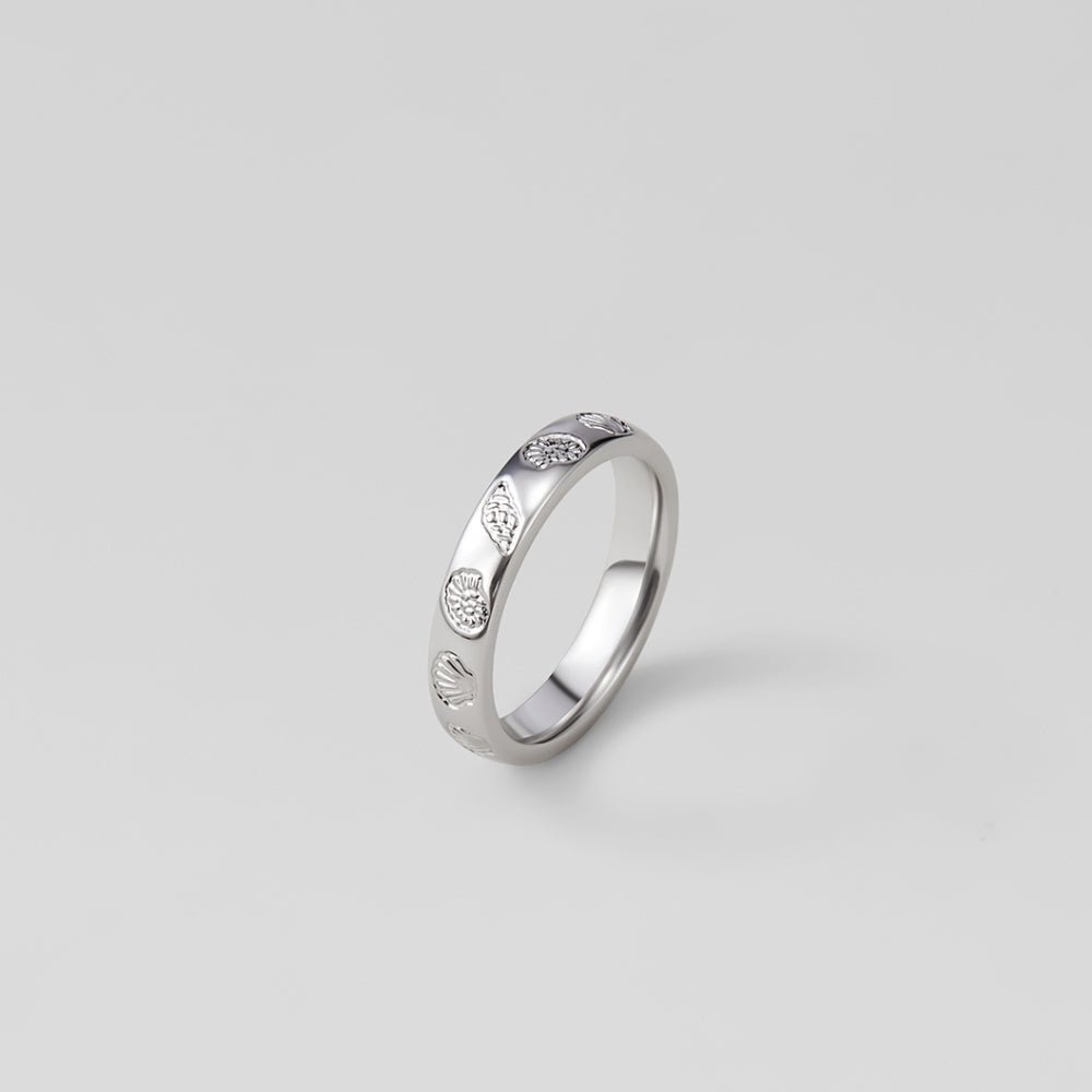 "Seascape" Engraved Silver Band Ring, standing upright on grey backdrop, shell pattern