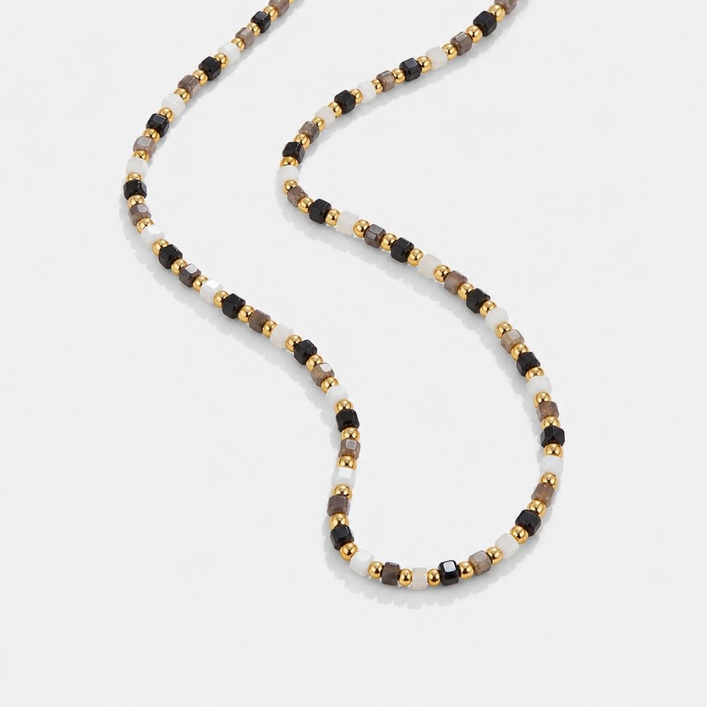 Alashan Monochrome Bead Necklace, beaded necklace laid in a loose curve on light grey