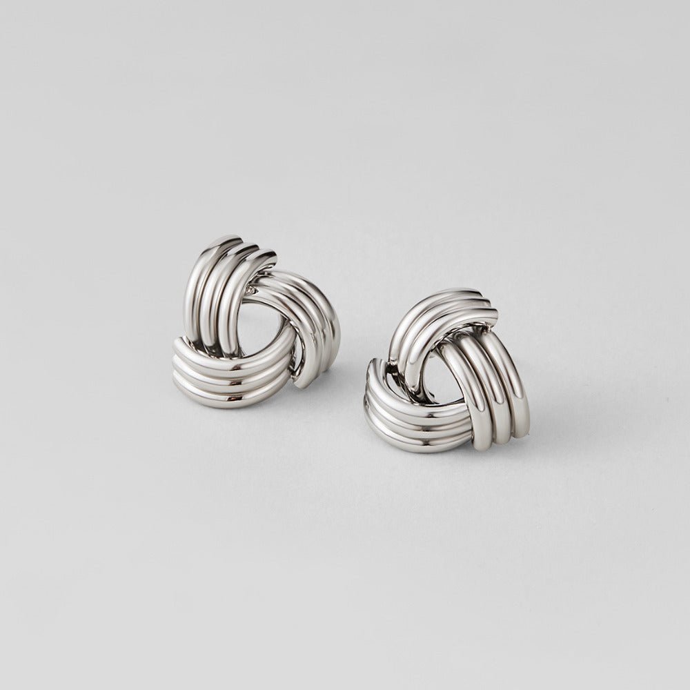 Silver Maxi Twist Stud Earrings, a pair of polished silver knot-shaped studs lying flat on grey