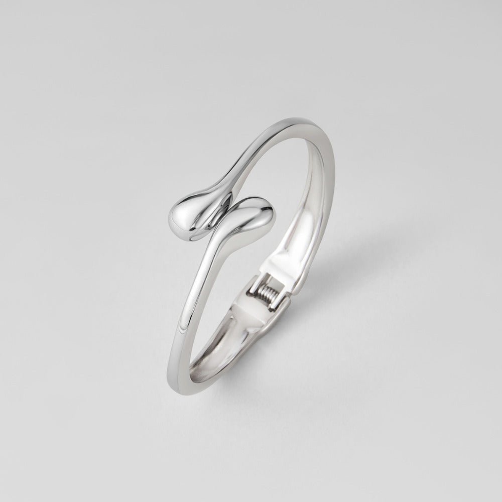 Silver Teardrop Bangle, silver bangle on a plain grey background, hinge clasp visible