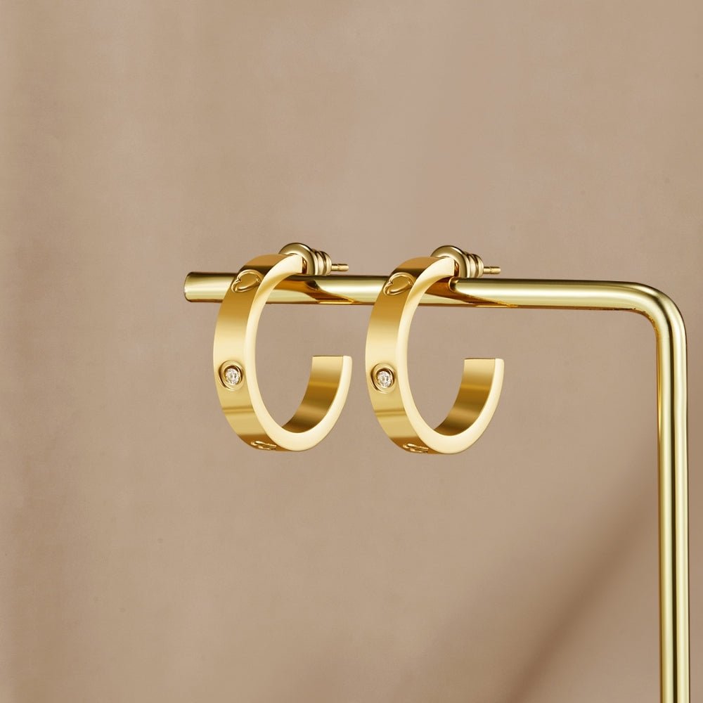 'Small Love' Hoop Earrings, a pair of gold hoops hanging on a gold display stand, with small stone accents